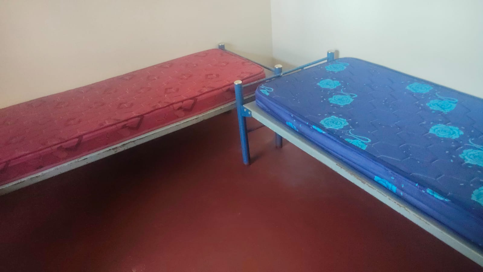 Single beds with mattresses inside a men's PG room in Tambaram, Chennai